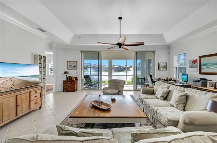 Tiled living room featuring a tray ceiling, plenty of natural light, and ornamental molding