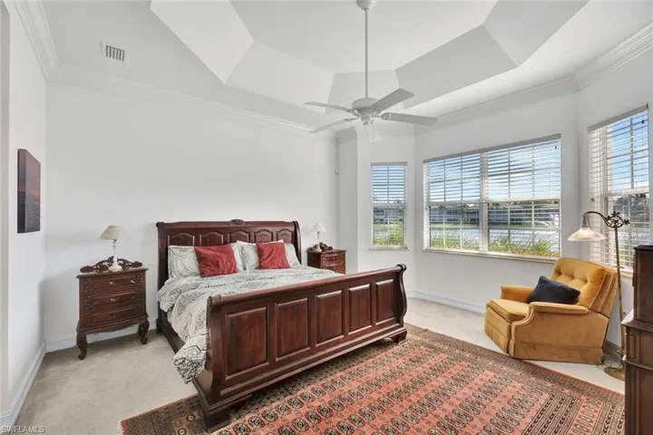 Bedroom featuring a tray ceiling, ceiling fan, light carpet, and ornamental molding