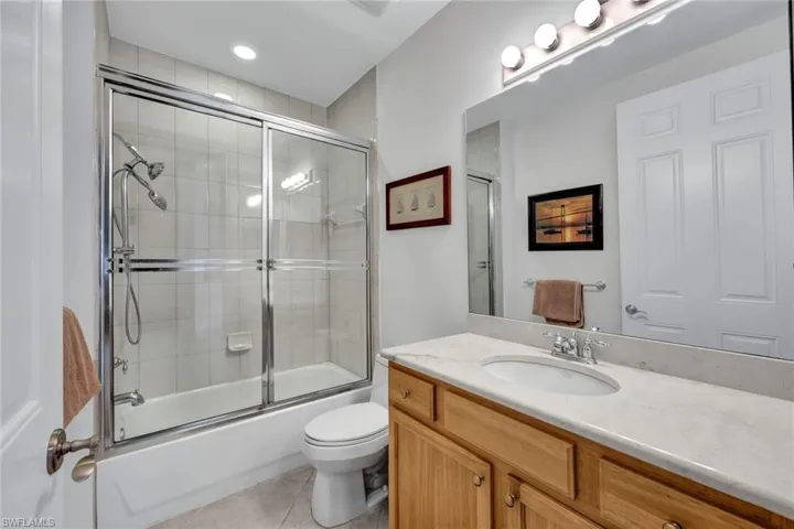 Full bathroom featuring toilet, tile patterned flooring, vanity, and combined bath / shower with glass door