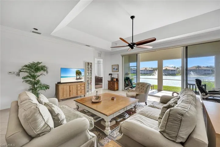 Living room with ceiling fan, light tile patterned floors, and crown molding