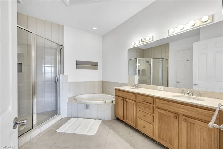 Bathroom featuring tile patterned flooring, shower with separate bathtub, and vanity