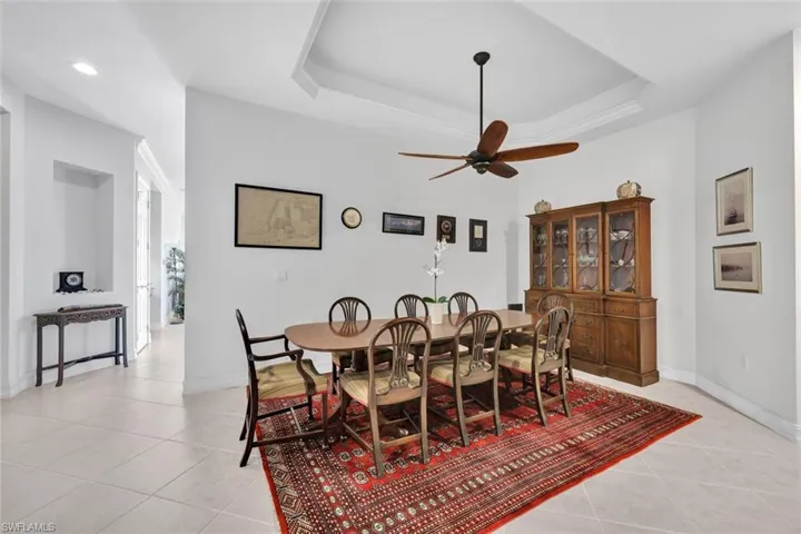 Tiled dining room featuring ceiling fan and a raised ceiling