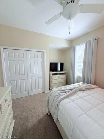 Carpeted bedroom featuring ceiling fan and a closet.