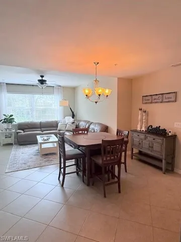 Living area and dining space featuring light tile patterned floors, ceiling fan, and hanging lights.