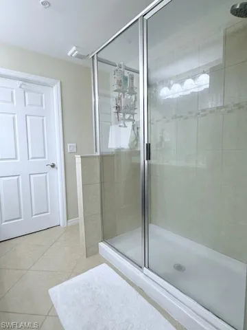 Full bathroom with a shower stall and light tile patterned flooring.