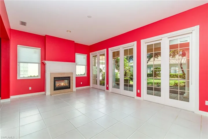 Unfurnished living room featuring light tile patterned flooring, french doors, and a glass covered fireplace