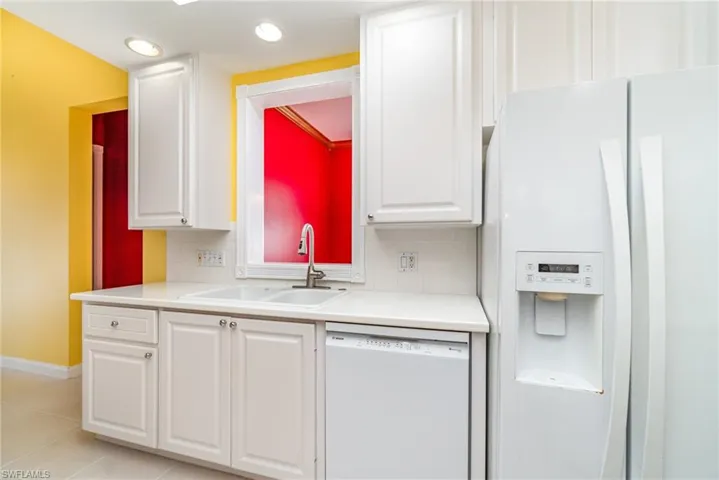 Kitchen featuring white appliances, light countertops, white cabinets, light tile patterned floors, and recessed lighting