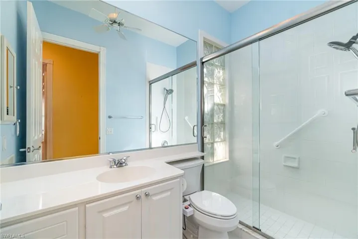 Full bathroom featuring vanity, a shower stall, and a ceiling fan