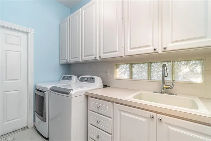 Laundry room with washing machine and clothes dryer, cabinet space, and light tile patterned flooring