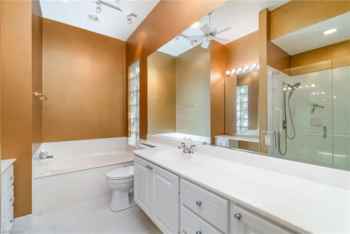 Bathroom with vanity, a garden tub, light tile patterned floors, a stall shower, and a ceiling fan