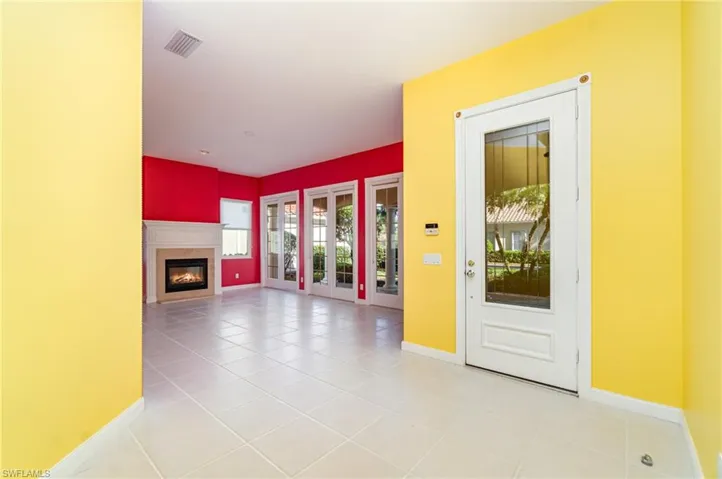 Unfurnished living room featuring light tile patterned floors and a glass covered fireplace