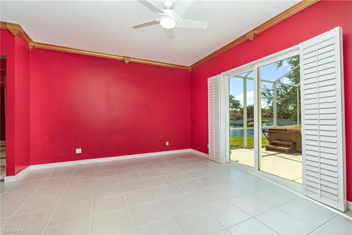 Empty room with crown molding, a ceiling fan, light tile patterned flooring, and a water view