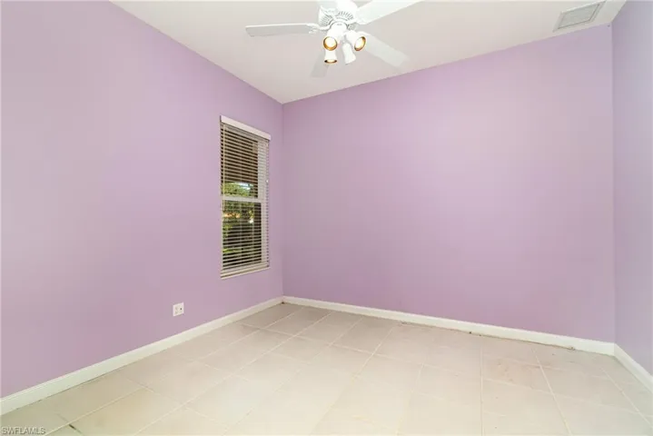 Empty room featuring light tile patterned flooring and a ceiling fan