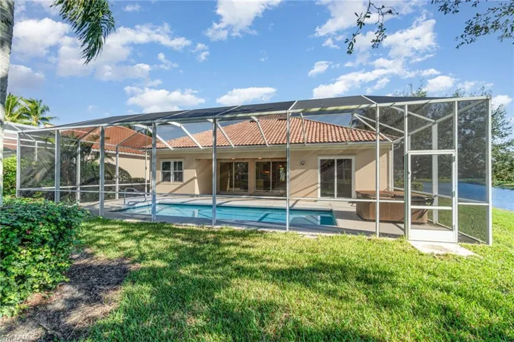 Rear view of property with a sunroom, a lanai, a tiled roof, and an outdoor pool