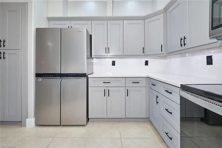 Kitchen featuring stainless steel appliances, light stone counters, and backsplash