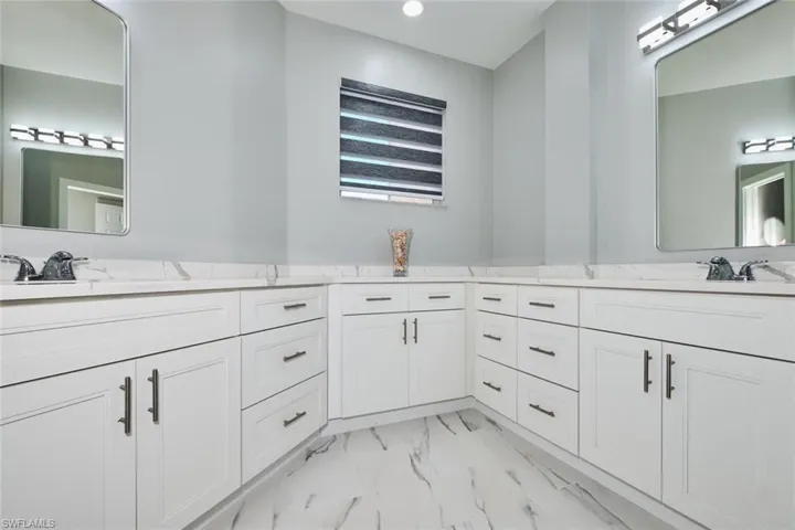 Bathroom with double vanity, recessed lighting, and light marble finish floors