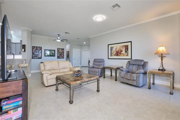 Tiled living area with ornamental molding and ceiling fan
