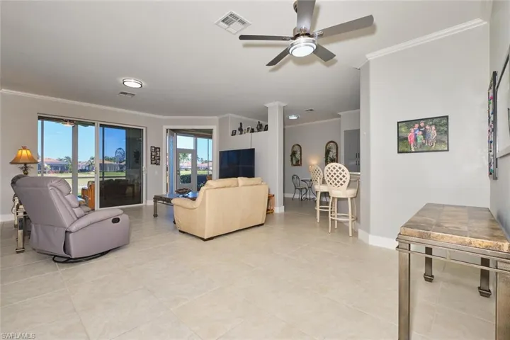 Living room with ornamental molding, a ceiling fan, and light tile patterned floors
