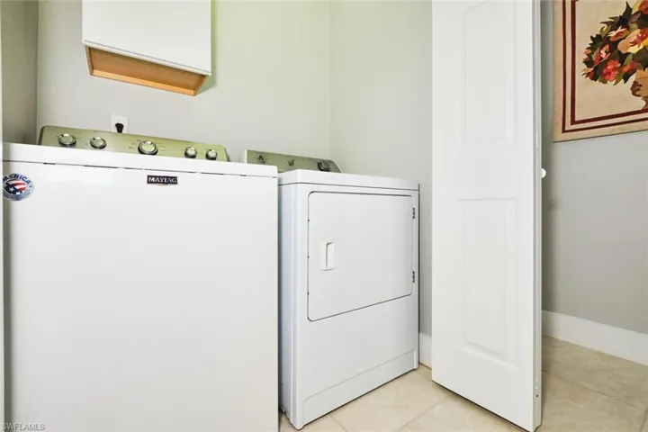 Laundry area with separate washer and dryer and light tile patterned floors