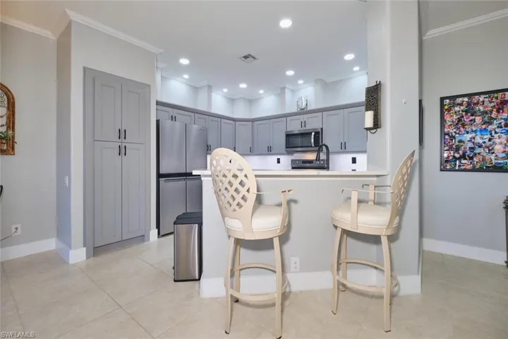 Kitchen featuring stainless steel appliances, a peninsula, a breakfast bar area, gray cabinetry, and crown molding