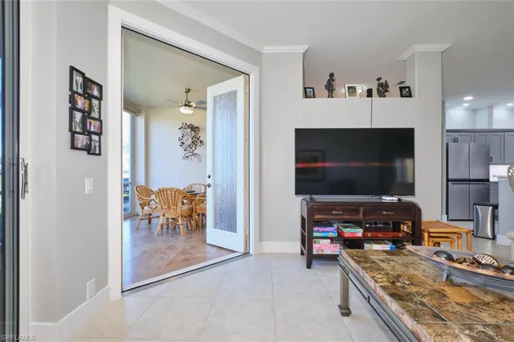 Living area with a ceiling fan, ornamental molding, and light tile patterned floors