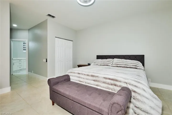 Bedroom with a closet, connected bathroom, and light tile patterned floors