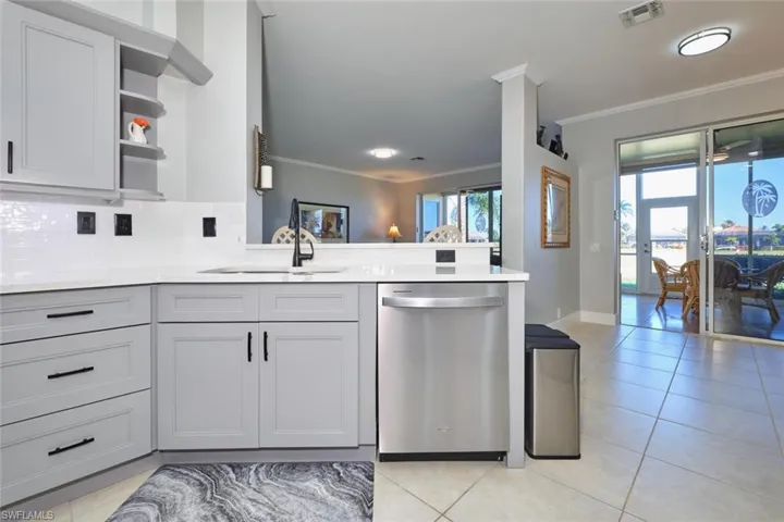 Kitchen featuring dishwasher, open shelves, decorative backsplash, gray cabinetry, and crown molding