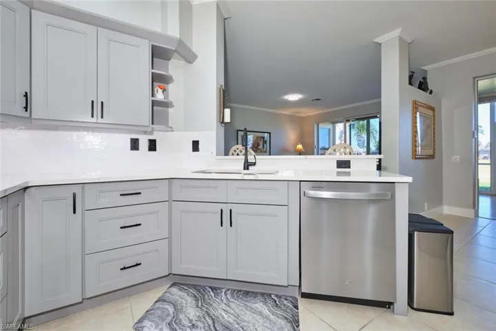 Kitchen featuring open shelves, ornamental molding, dishwasher, tasteful backsplash, and gray cabinetry