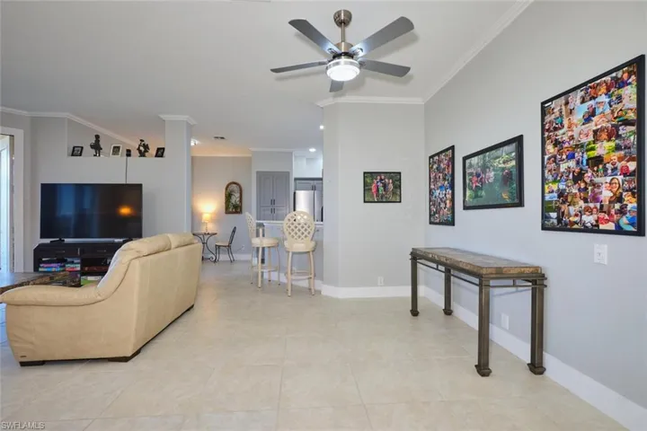 Living room featuring crown molding, a ceiling fan, and light tile patterned floors