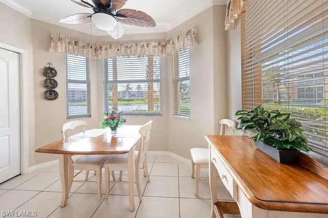 Tiled dining space with ceiling fan and ornamental molding