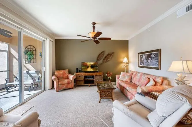 Carpeted living room with ornamental molding and ceiling fan