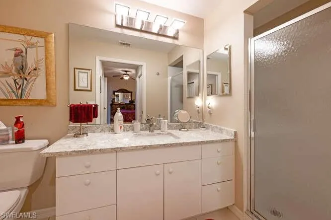 Bathroom with toilet, an enclosed shower, vanity, and ceiling fan