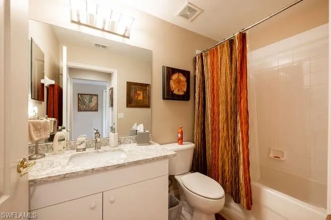 Full bathroom featuring vanity, shower / bath combo, and toilet