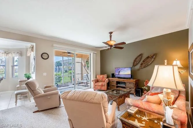 Living room featuring ceiling fan, ornamental molding, and light tile patterned floors