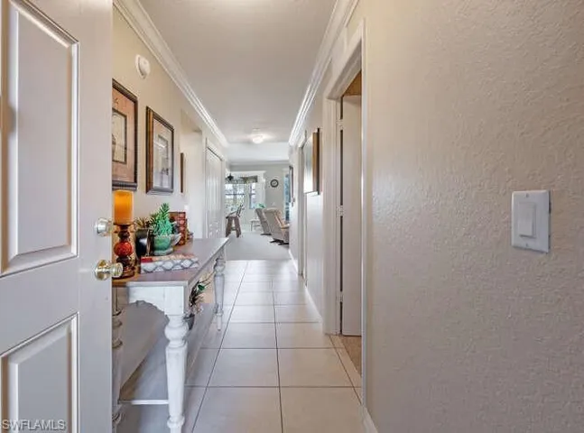 Hallway with ornamental molding and light tile patterned floors