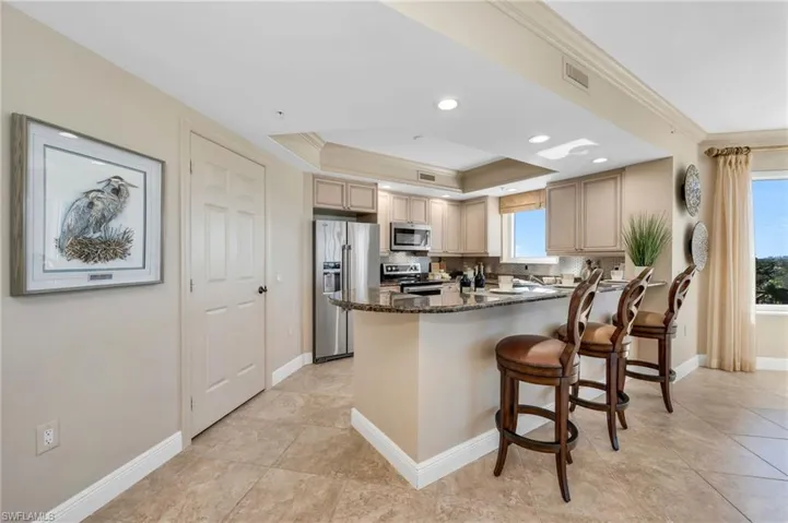 Kitchen with granite counters, a tray ceiling, walk-in pantry, stainless steel appliances and breakfast bar