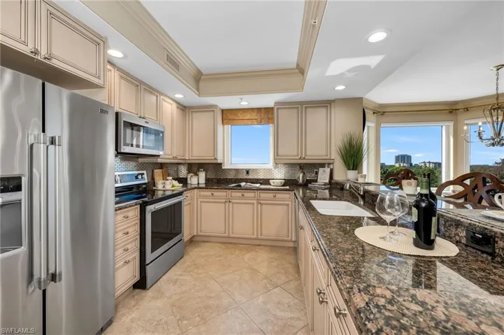 Kitchen with crown molding, stainless steel appliances, dark stone countertops, decorative backsplash, and recessed lighting