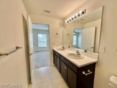 Bathroom featuring a dual vanity with dark wood cabinetry, white countertops, and integrated sinks