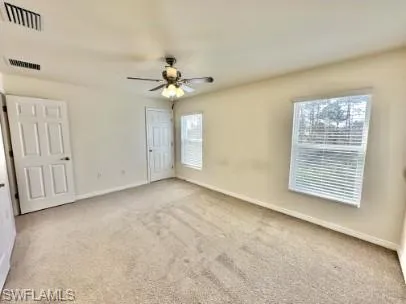 Spacious room with neutral carpeting, light-toned walls, and a ceiling fan with integrated lighting