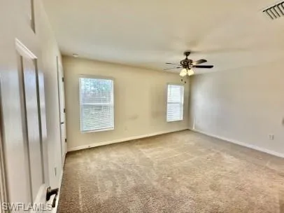 Carpeted room featuring two windows with white blinds, a ceiling fan with light fixture, and neutral painted walls