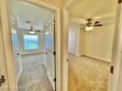 Two carpeted rooms with neutral wall colors and ceiling fans