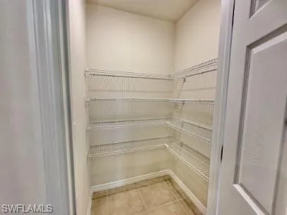 Walk-in pantry featuring light-colored walls, tile flooring, and multi-level wire shelving