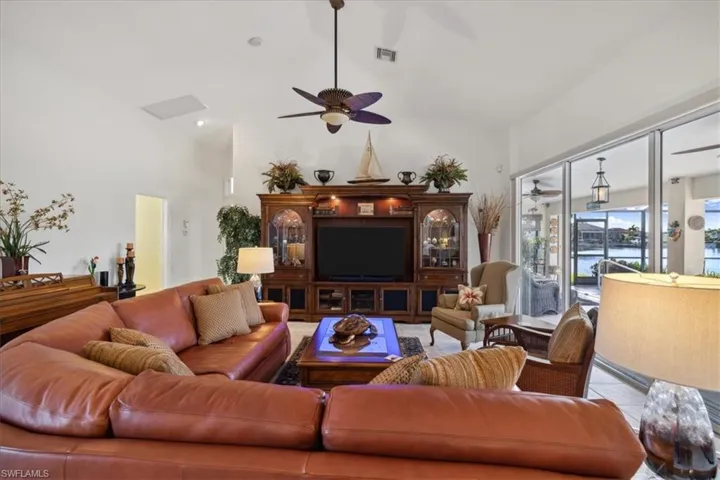 Living room with a towering ceiling, tile flooring, and ceiling fan