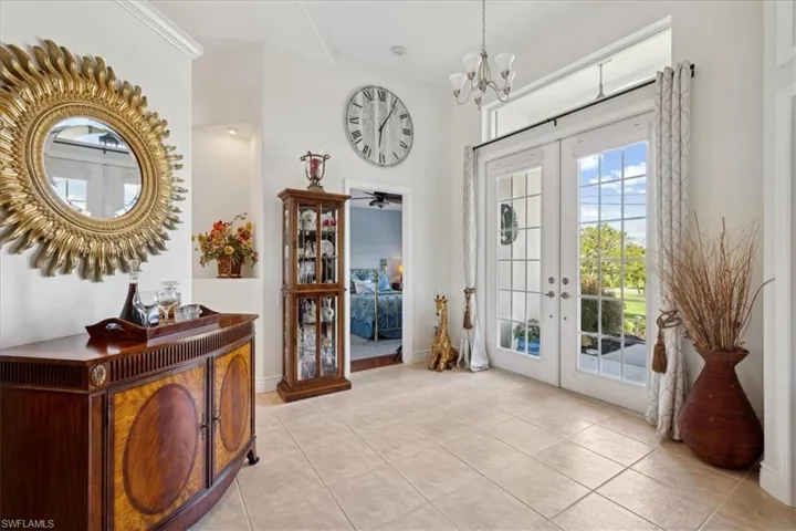 Entryway with light tile floors, an inviting chandelier, and french doors