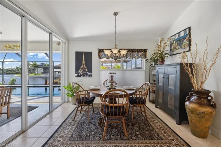 Tiled dining area featuring vaulted ceiling, a water view, and an inviting chandelier