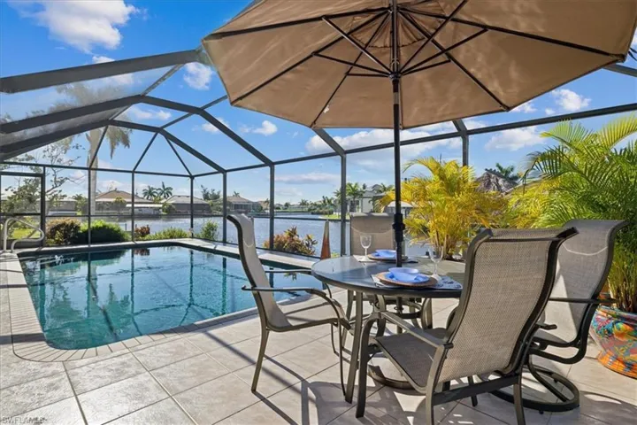 View of swimming pool featuring a patio area, glass enclosure, and a water view