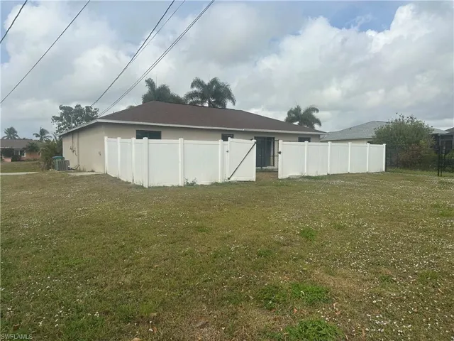 Back of house featuring central air condition unit and a yard