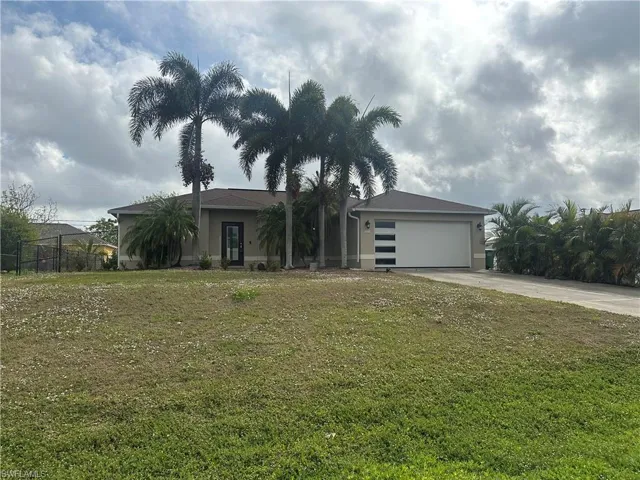 View of front of property with a front yard and a garage
