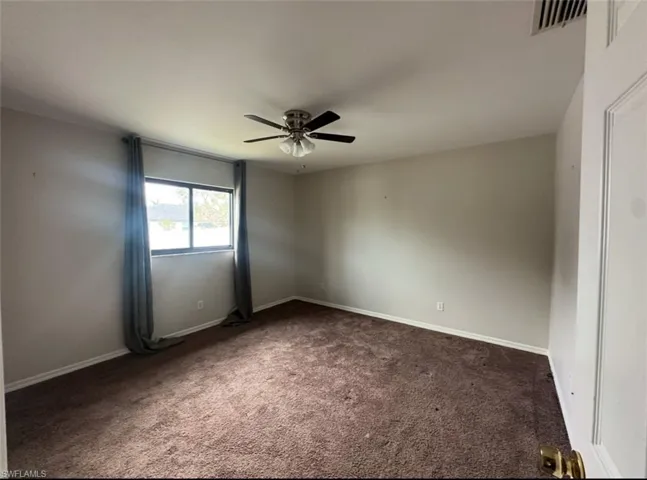 Unfurnished room featuring dark carpet and ceiling fan