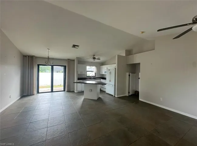 Kitchen featuring dark countertops, freestanding refrigerator, hanging light fixtures, open floor plan, and white cabinets